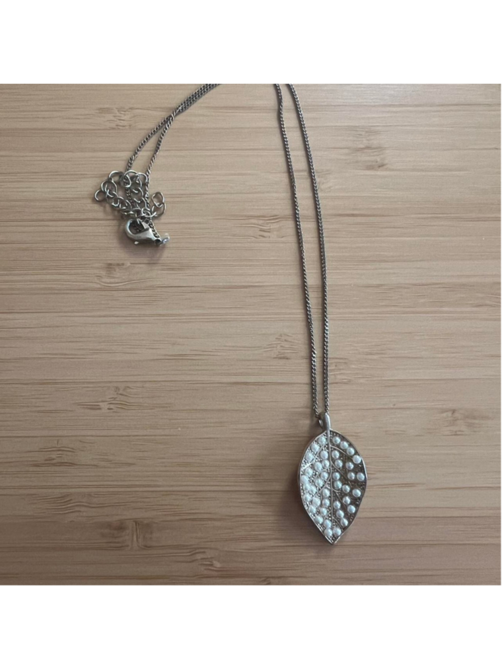 Gold necklace with a leaf pendant and pearl accents